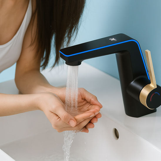 femme cheveux noir long lave ses mains dans lavabo sous mitigeur lavabo noir à poignée dorée