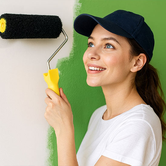 femme souriante avec casquette bleue et pull blanc , peint en vert avec Rouleau peinture