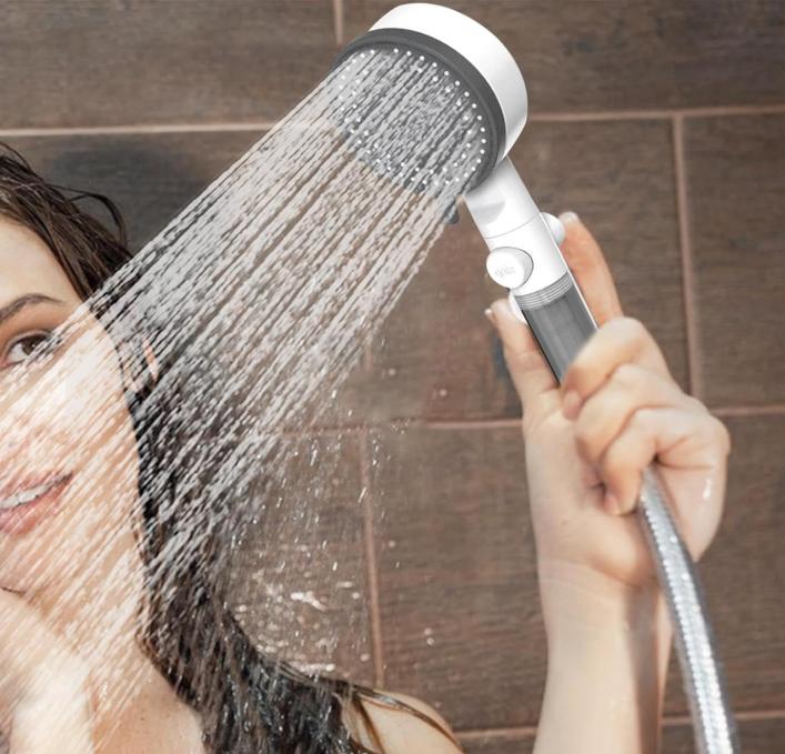 femme souriante tient Pommeau de douche anti calcaire en mode pluie sur son visage