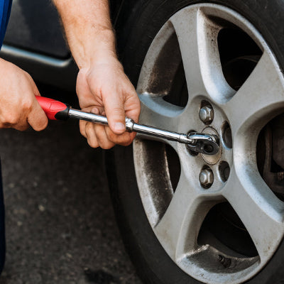homme demonte avec ses deux mains l'ecrou de voiture avec CLE A cliquet , poignee antiderapante