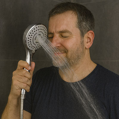 homme devant Pommeau de douche mode pulsations au visage