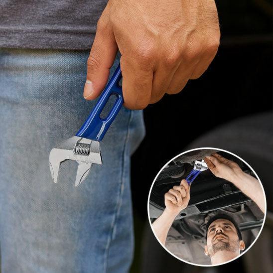 mecanicien en jean repare dessous voiture avec CLE A molette à poignee ergonomique bleue