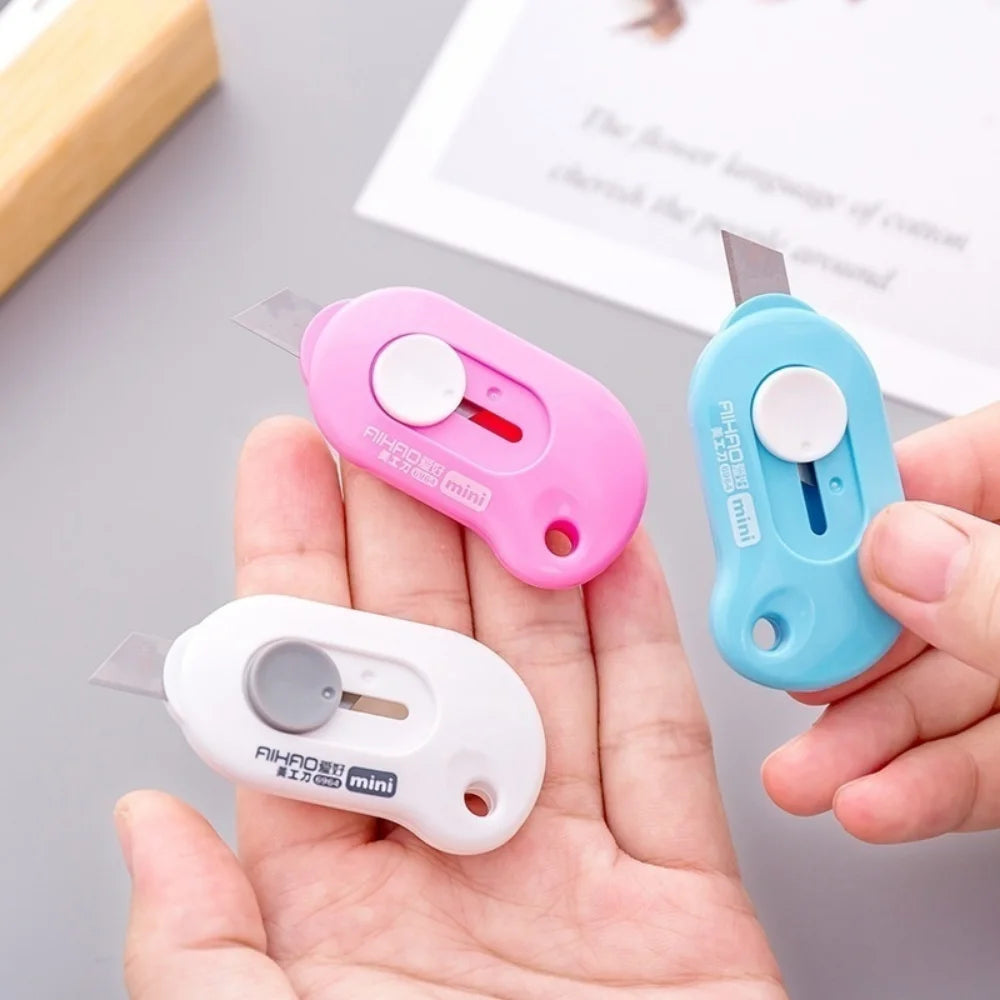 Trois cutters blanc rose et bleu dans les mains