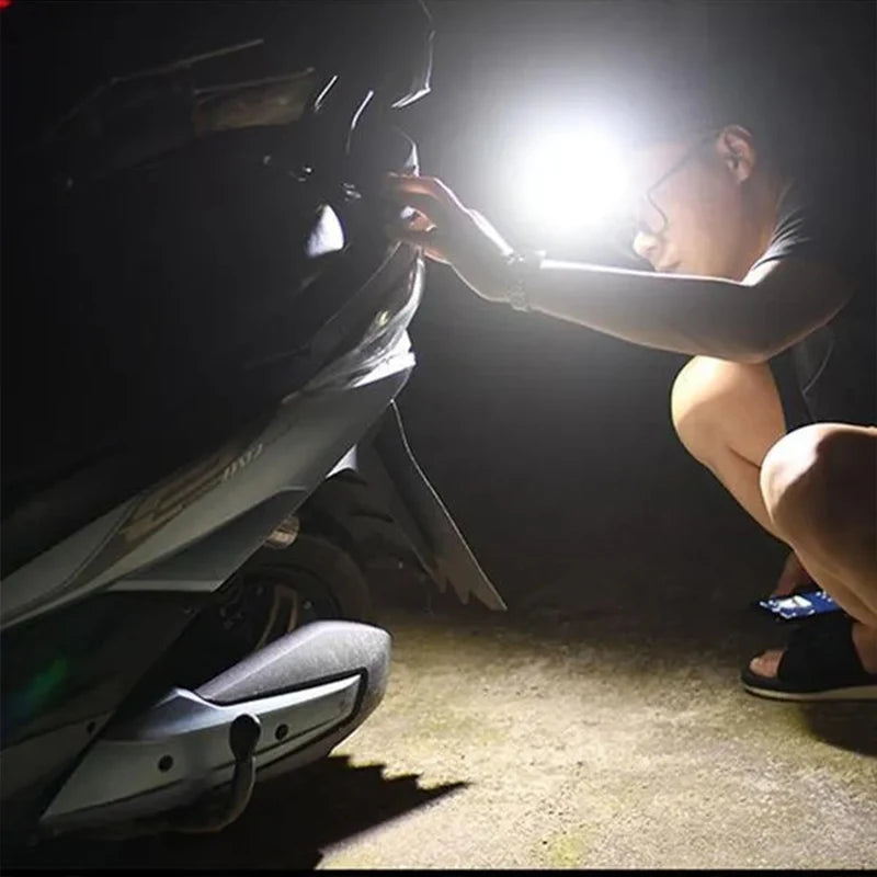 Lampe Frontale allumee portee par un homme repare la voiture la nuit