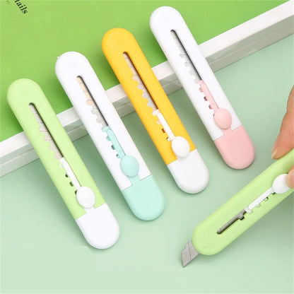 Cinq mini cutter animal, verts, blancs et jaune tenus par une main, sur la table