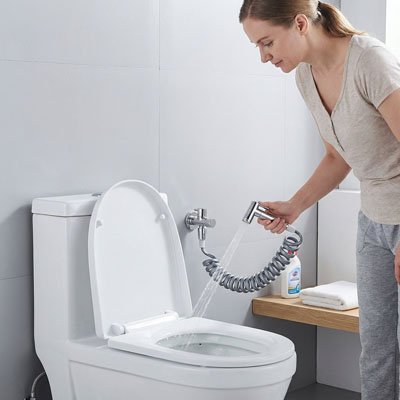 femme debout nettoie siege wc anglais avec Douchette WC chromee suspendue au mur