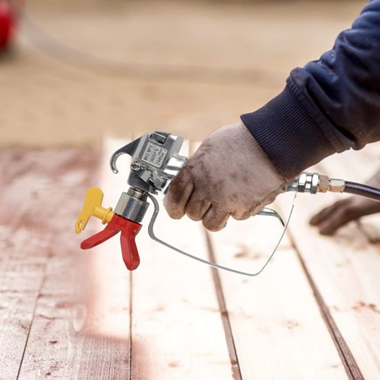 homme manche bleue peint avec Pistolet peinture jaune et rouge , plancher  bois en marron