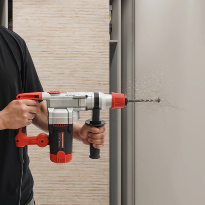 Homme avec pull noir perce mur béton avec perceuse perforatrice rouge et blanc, marteau perforateur
