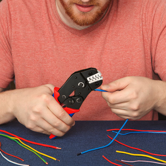 homme utilise Pince a sertir,  poignee  ergonomique rouge bleue de la Pince a sertir fils toute couleur