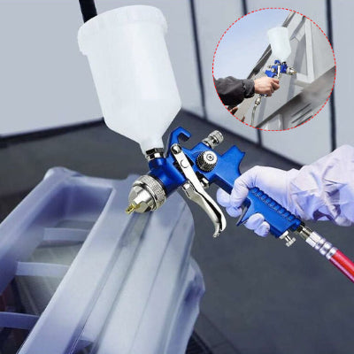 Main tenant Pistolet peinture bleu avec réservoir blanc pulvérise 