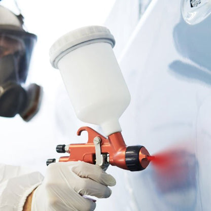 peintre tenue blanche peint avec Pistolet peinture orange la voiture en rouge