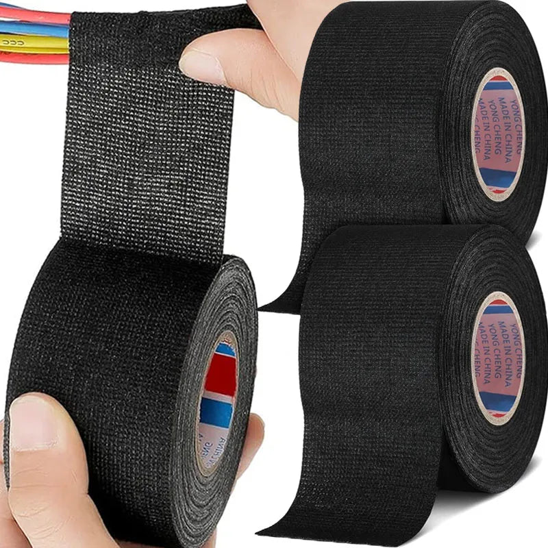 trois rouleaux de  ruban adhesif ignifuge noir, main enroule  ruban adhesif sur cable multifilaires multicolor